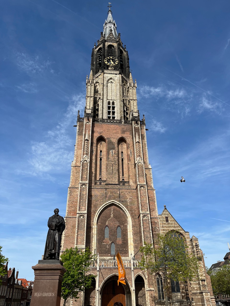 Tower of the New Church in Delft with a bird in a clear blue sky