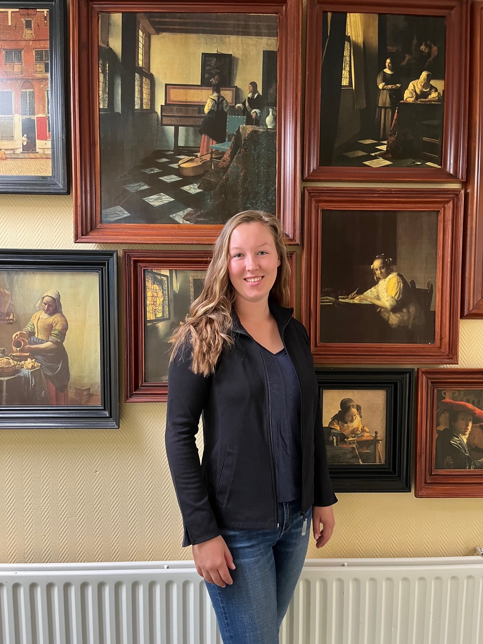 Maddie smiles before replica paintings at Johannes Vermeer Hotel