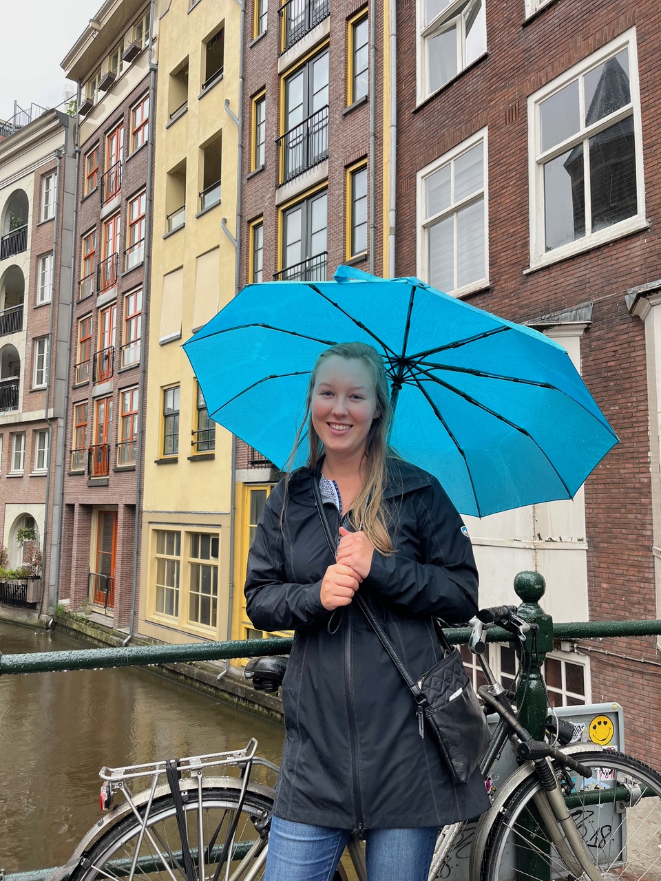 Maddie in the streets of Amsterdam with blue umbrella
