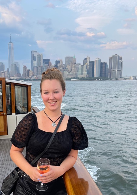 Maddie on the boat with the skyline of New York City in the background