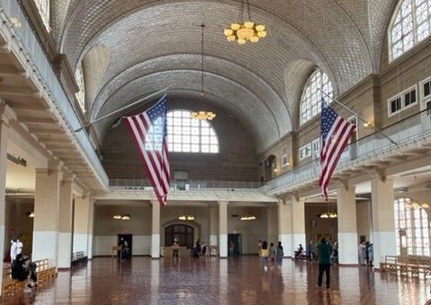 Interior hall of Ellis Island with a second level gallery and two American flags
