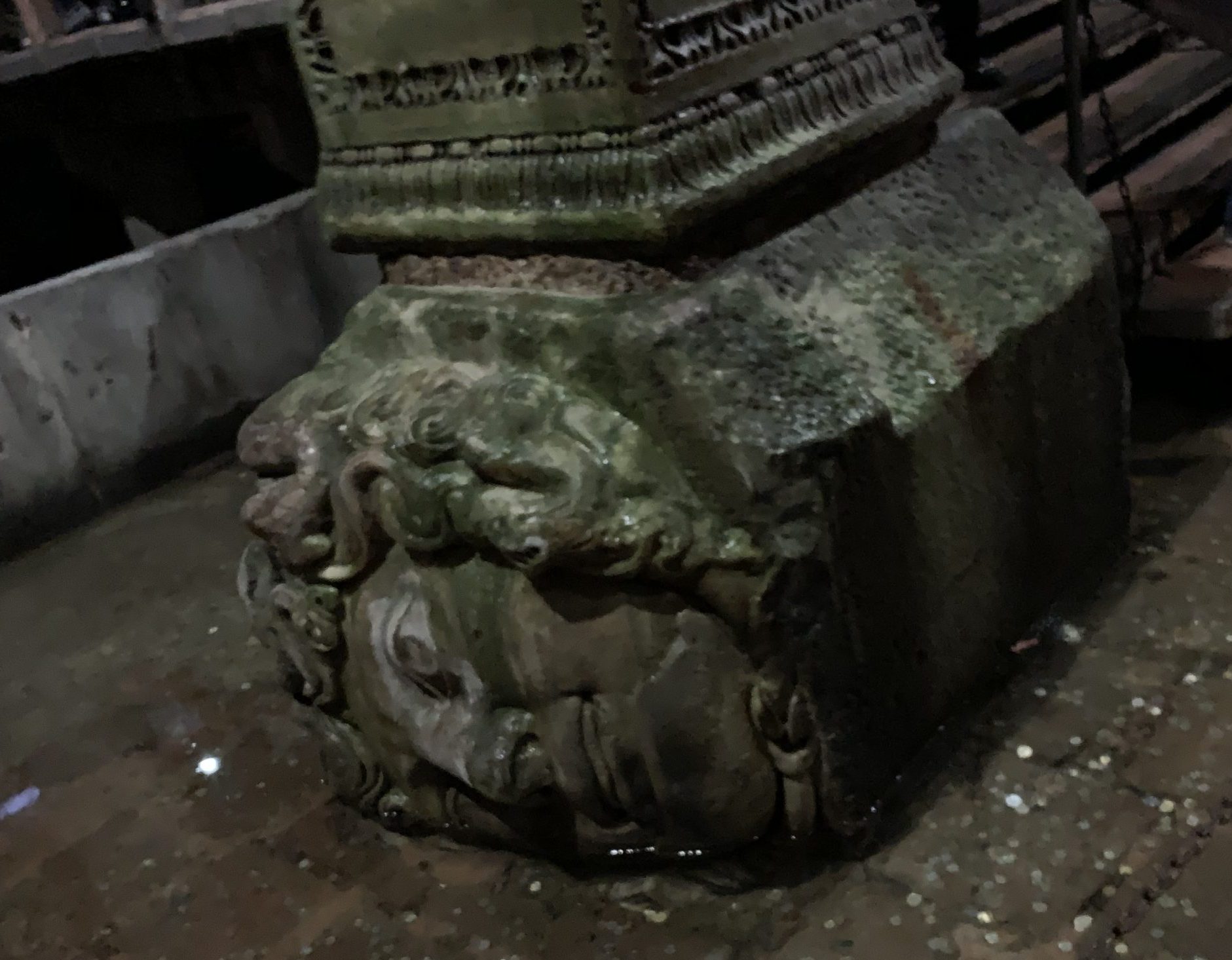 sideways stone Medusa head with a pillar on top