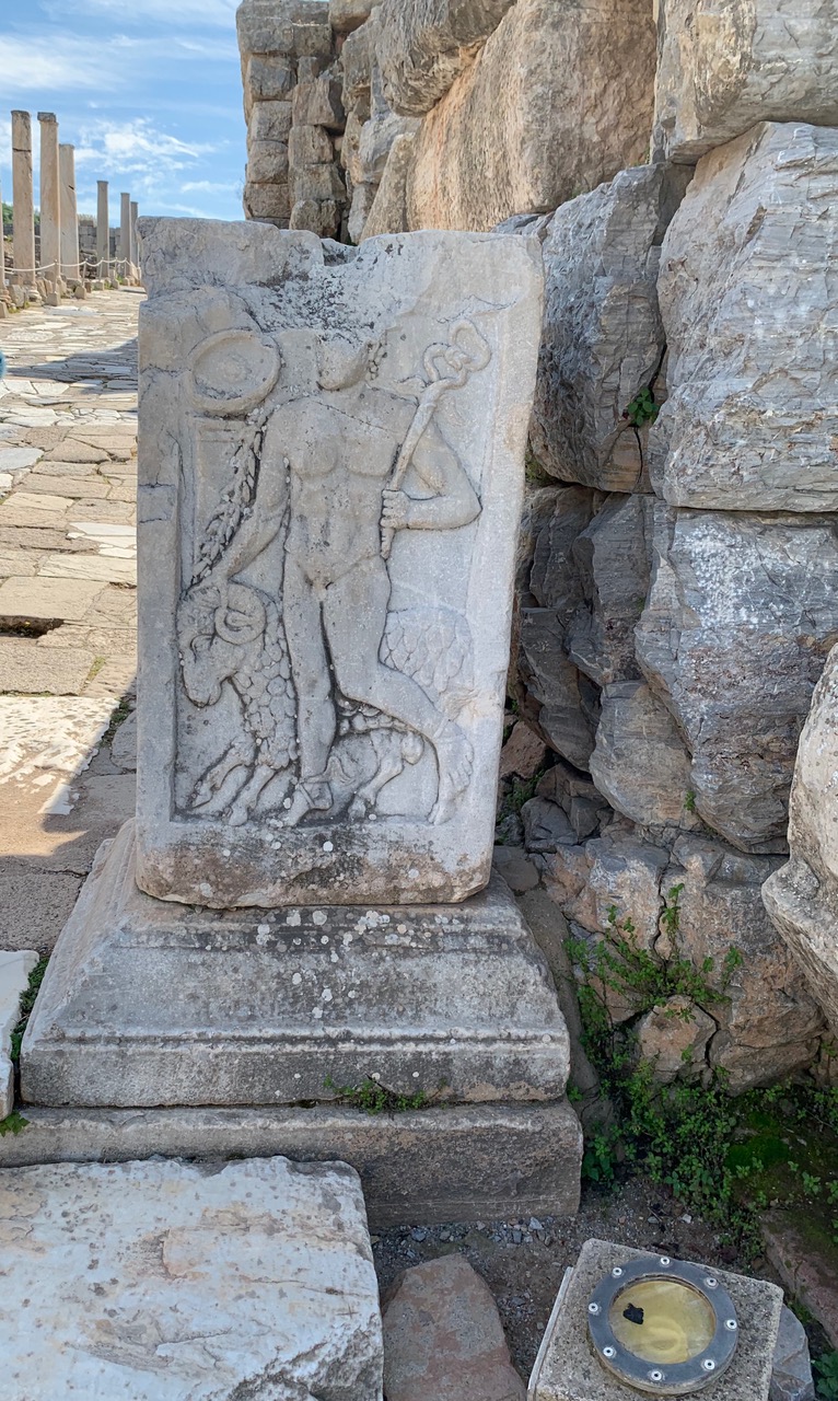 Carved image of a naked man and a ram on a slab of marble