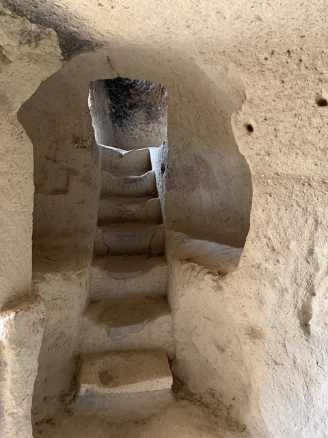 stairs descending into a rock-cut church carved out of the tufa