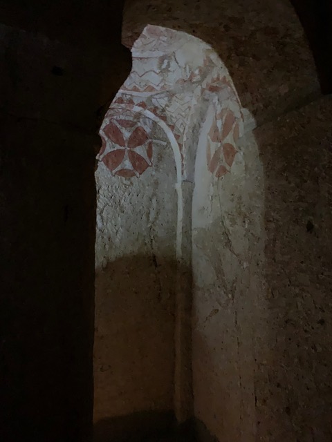 shadowed entry way of a rock-cut church painted with red