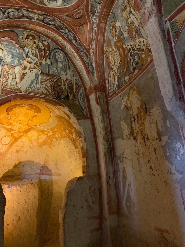 frescoed arch of a rock-cut church with patterns of red and blue and figures of saints
