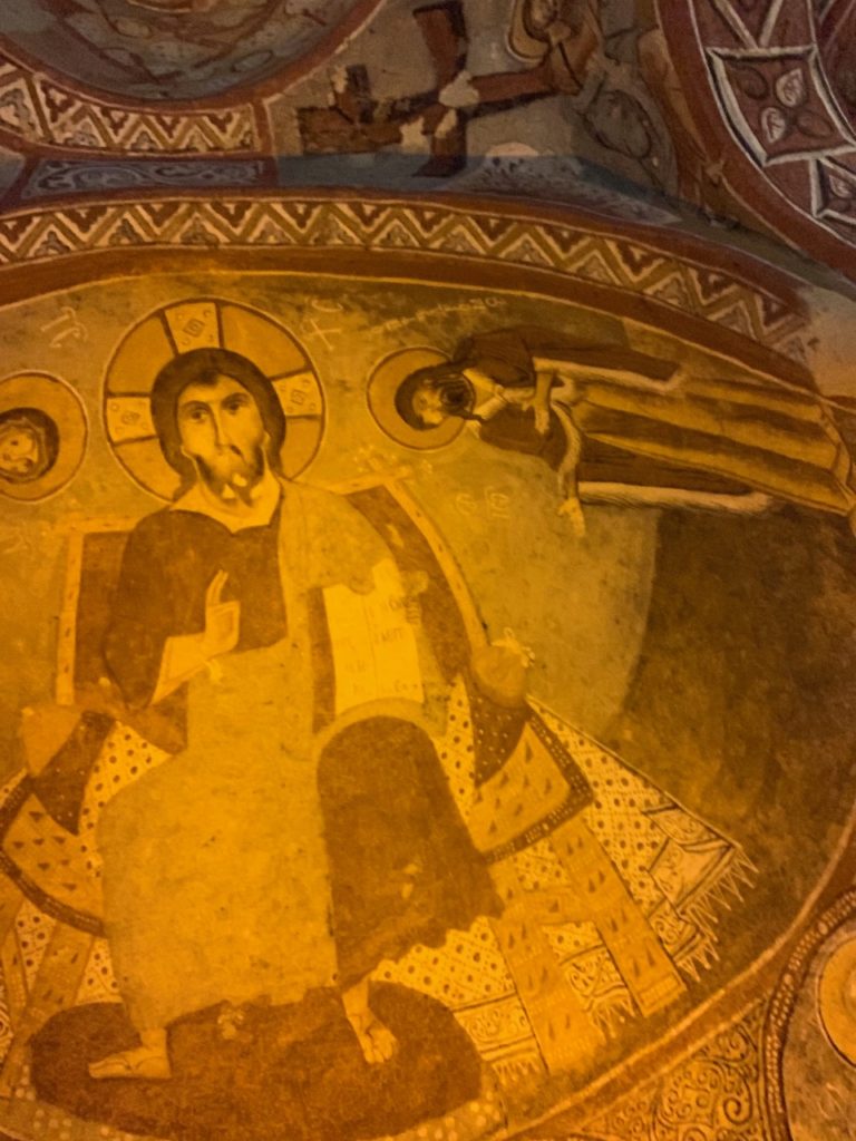 fresco on the carved interior dome of a rock-cut church showing Jesus with an orthodox halo around his head