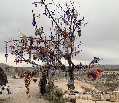 Tree bare of leaves with evil eye decorations of a blue stone with white paint in the center adorning every branch