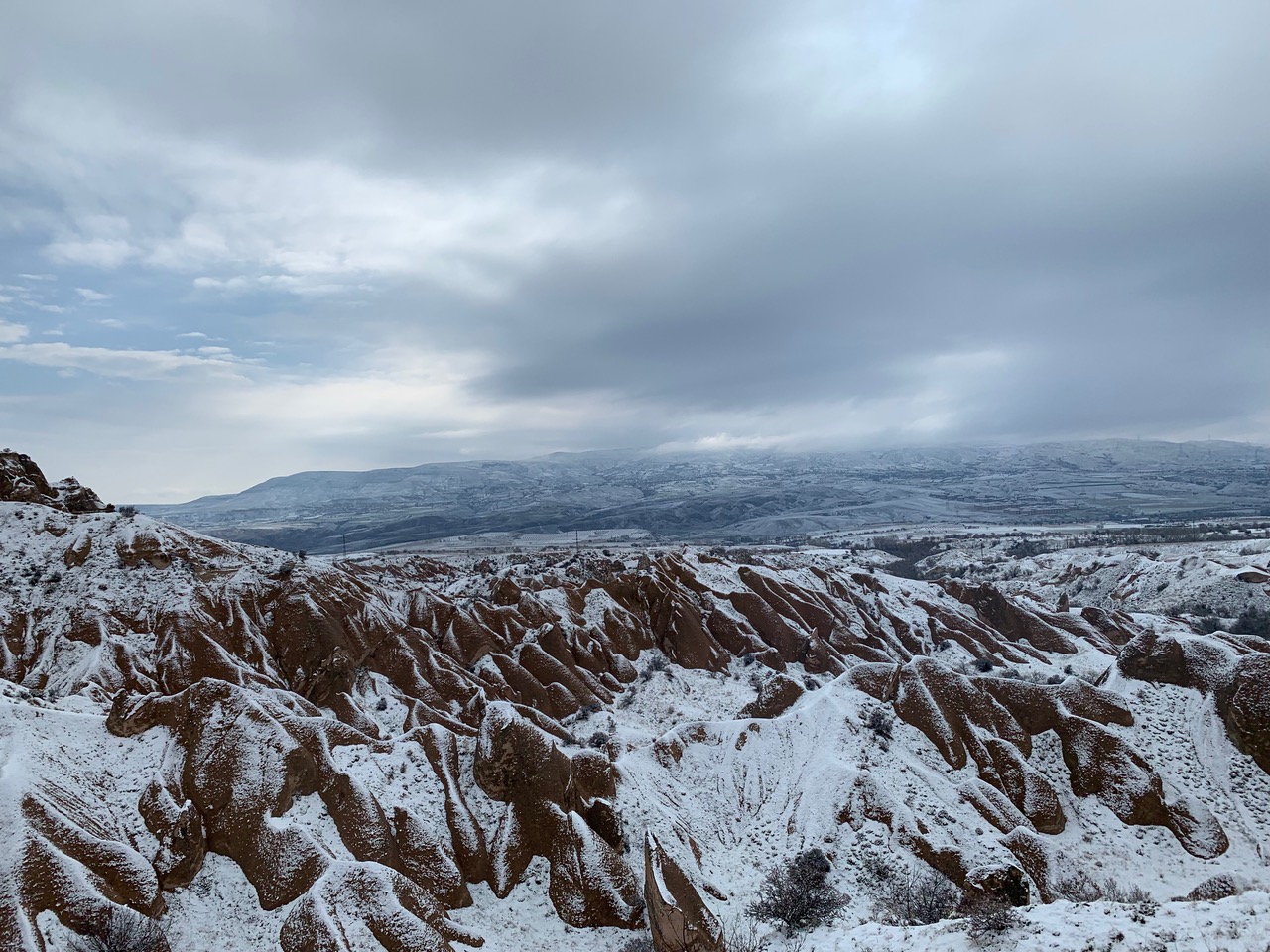 light dusting of snow over a red-ish landscape of tufa formations