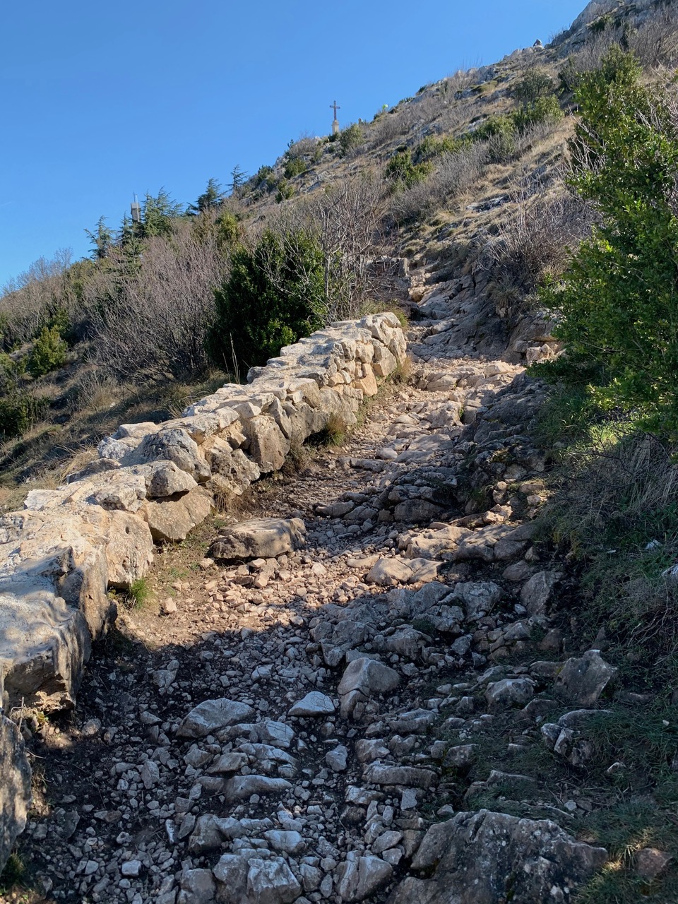 Rocky path to the top of Montagne Sainte-Victoire with the cross barely visible against the blue sky