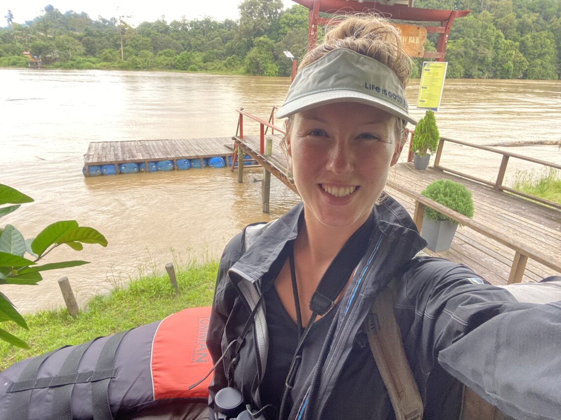 Maddie with a visor and binoculars waiting to get on a boat to explore the Kinabatangan River